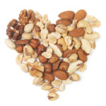 Various nuts forming heart shape on white background