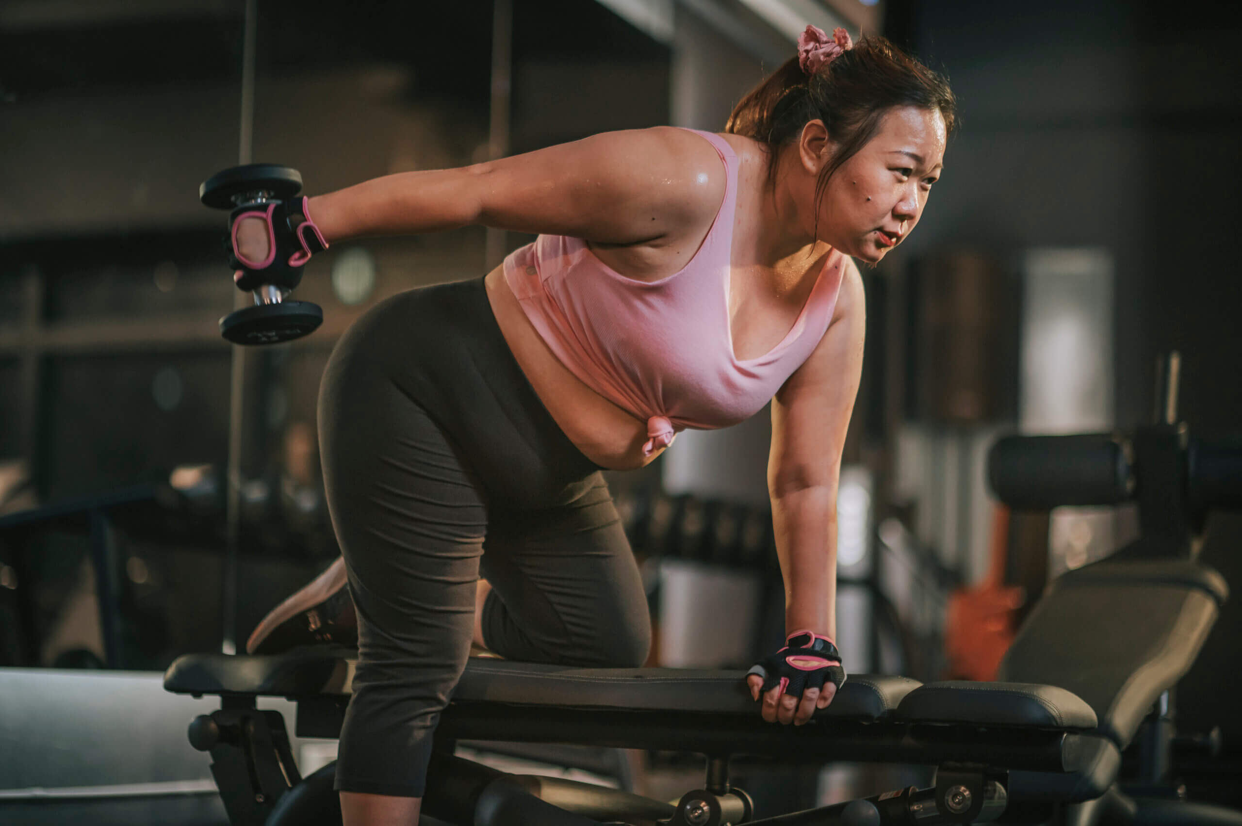 woman using dumbbells in a lunge position at gym at night