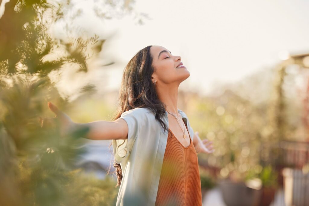 person standing outside smiling with arms outstretched