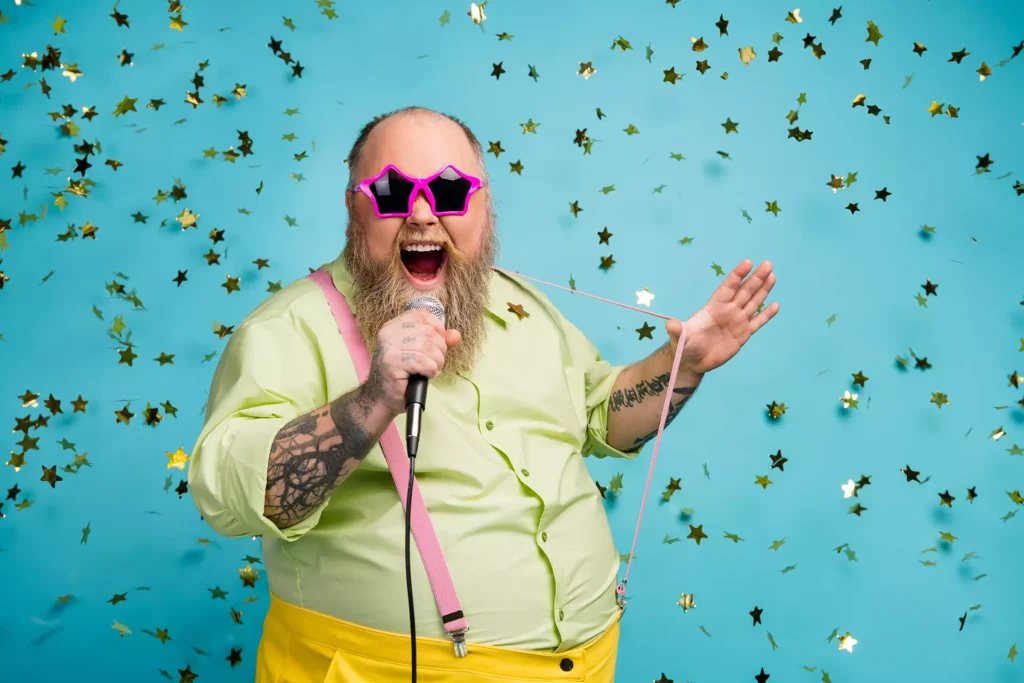 Person wearing sunglasses holding microphone with confetti