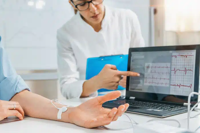 person experiencing biofeedback with a heart rate monitor on their wrist and results on a laptop