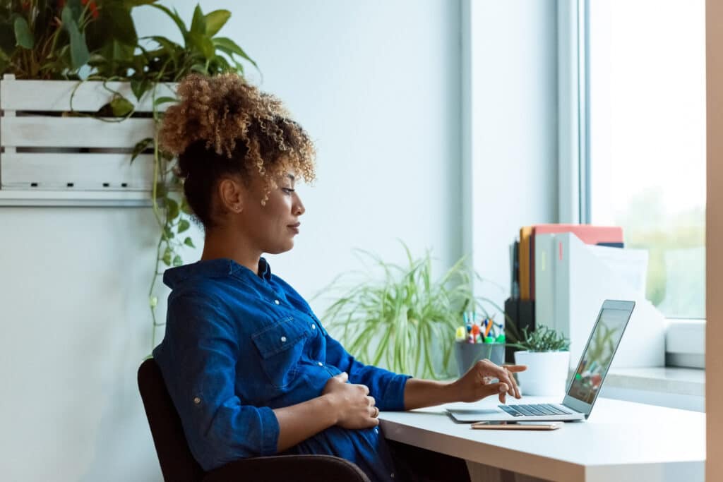 pregnant person looking at laptop